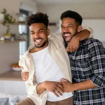 Young adult brothers in kitchen indoors at home, having fun