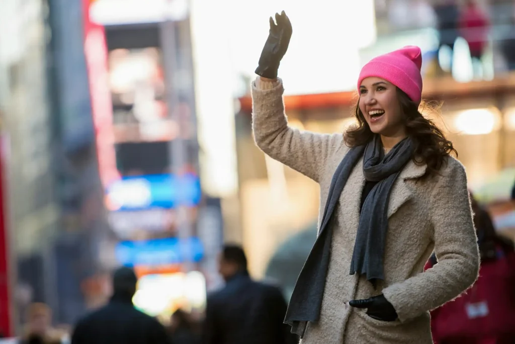 Young female tourist waving from street, New York City, USA